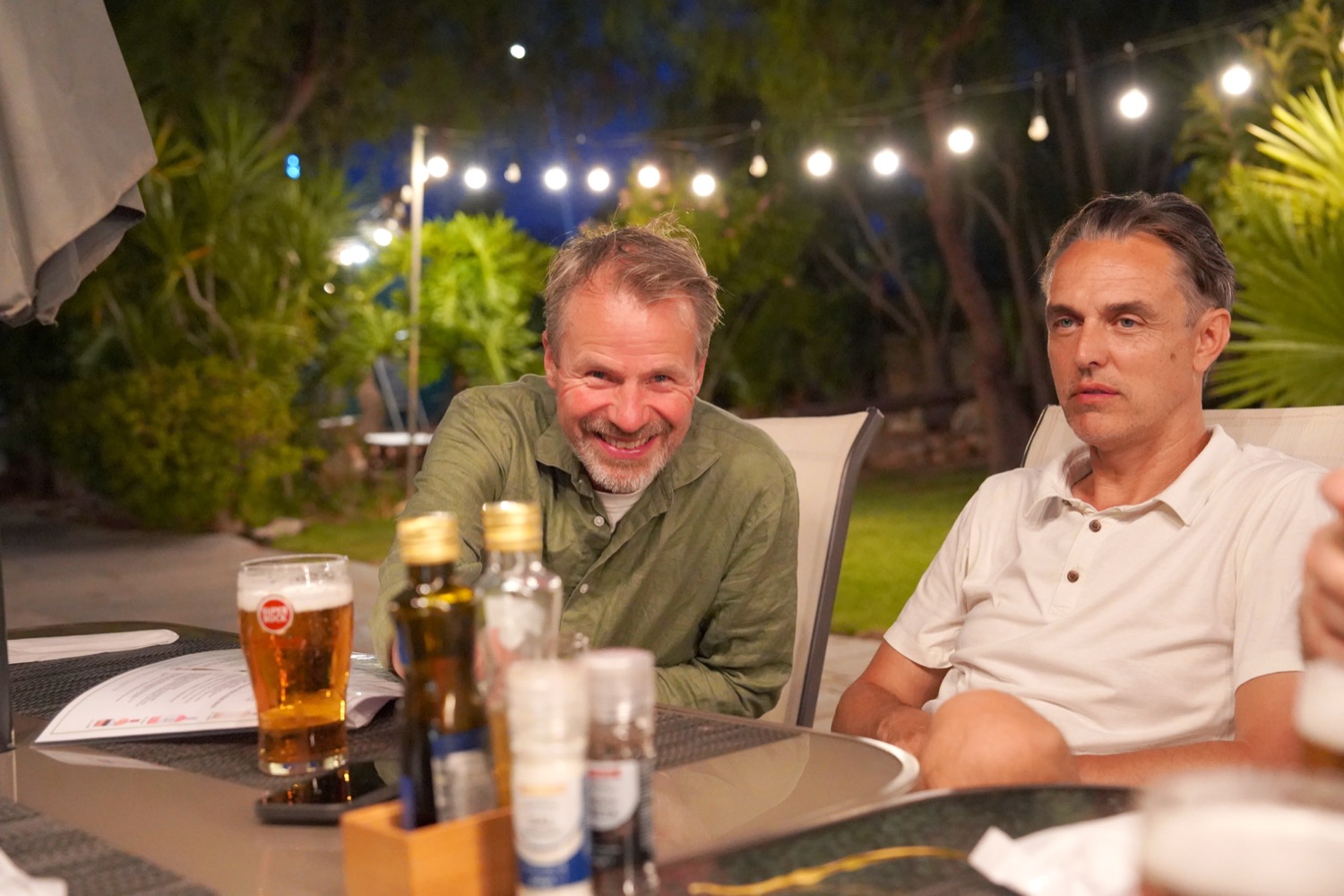 Two founders talking over dinner under string lights
